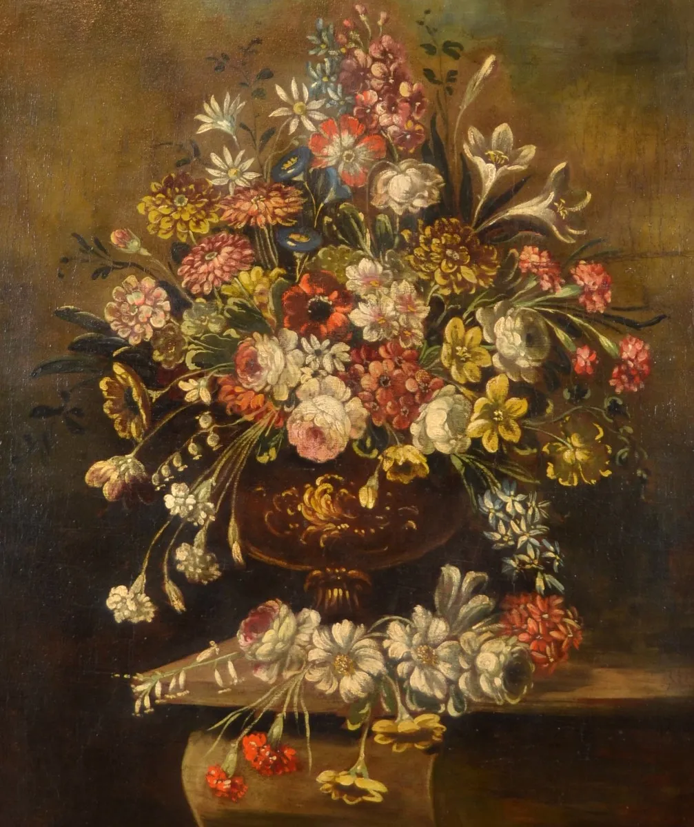 L'image est une peinture représentant une nature morte : un large bouquet de fleurs variées est disposé dans un vase à pied en bronze. Le vase est posé sur l'angle d'une table. Plusieurs fleurs reposent également sur la table.