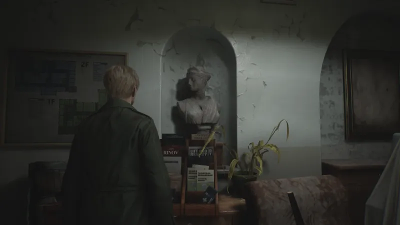 Capture d'écran de Silent Hill 2 qui montre le personnage de James Sunderland de dos. Il fait face à une petite alcove dans laquelle est exposée un buste qui reprend le modèle de la sculpture antique dite "Diane de Versailles"