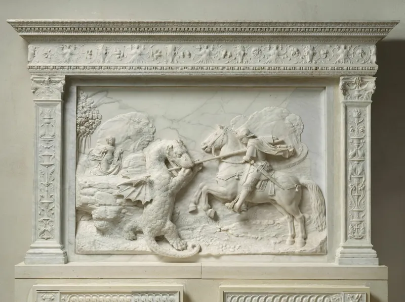 L'image est la photographie d'un bas-relief en marbre représentant le combat d'un cavalier (à droite) et d'un dragon (à gauche). On apperçoit au second plan, à gauche, une jeune femme qui observe la scène.