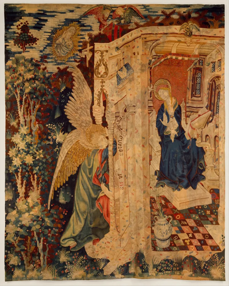 L'image est une tapisserie qui représente un ange (à gauche) se présentant à la porte d'une petite habitation occupée par une jeune femme. Il s'agit de la scène biblique de l'Annonciation.