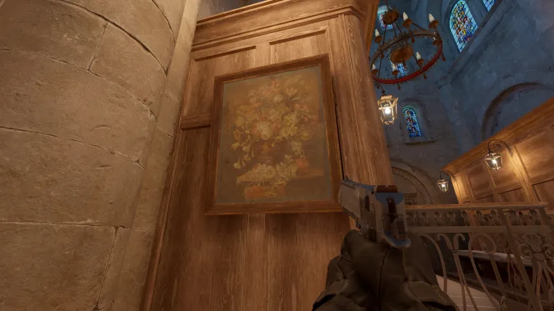 L'image est une capture d'écran du jeu Counter-Strike 2. On y voit l'intérieur d'une chapelle dans laquelle est accroché, dans un angle, un tableau représentant une nature morte de fleurs.