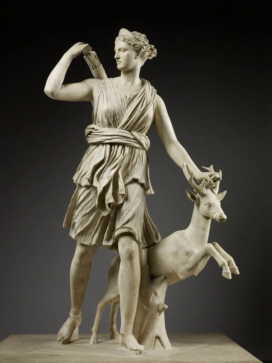 Sculpture en marbre représentant la déesse Diane sous les traits d'une jeune femme vêtue d'une tunique, prise dans une attitude de course. Elle tient dans sa main gauche un arc brisé dont il ne reste plus que la poignée, et de sa main droite elle cherche une flèche dans le carquois qu'elle a dans le dos. Un jeune cerf s'élance à ses côtés.