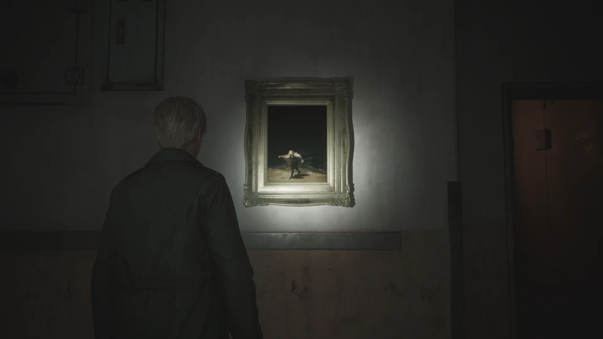 Capture d'écran de Silent Hill 2 qui montre le personnage de James Sunderland de dos. Il fait face à un mur sur lequel est accroché le tableau "Le Vol des Sorcières" de Francisco de Goya