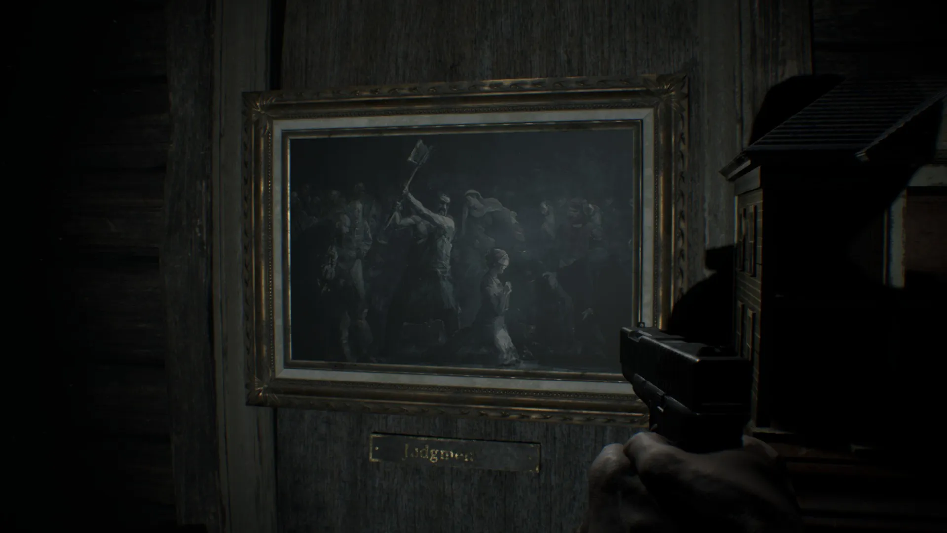 L'image est une capture d'écran du jeu Resident Evil 7. La caméra, qui adopte le point de vue du personnage joueur, nous montre un mur auquel est accrochée une peinture en grisaille représentant l'exécution d'une jeune femme. Elle se tient à genoux au centre de la représentation, tournée vers la droite. Derrière elle, un bourreau lève sa hache. Tout autour de nombreux personnages assistent à la scène.