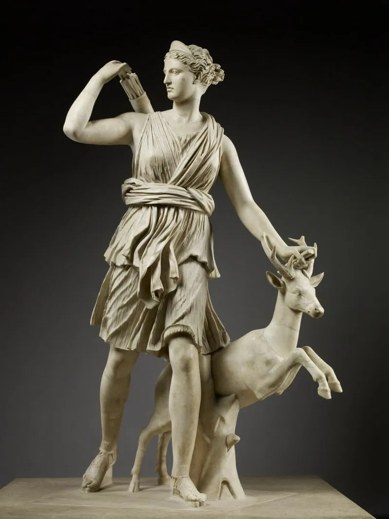Sculpture en marbre représentant la déesse Diane sous les traits d'une jeune femme vêtue d'une tunique, prise dans une attitude de course. Elle tient dans sa main gauche un arc brisé dont il ne reste plus que la poignée, et de sa main droite elle cherche une flèche dans le carquois qu'elle a dans le dos. Un jeune cerf s'élance à ses côtés.